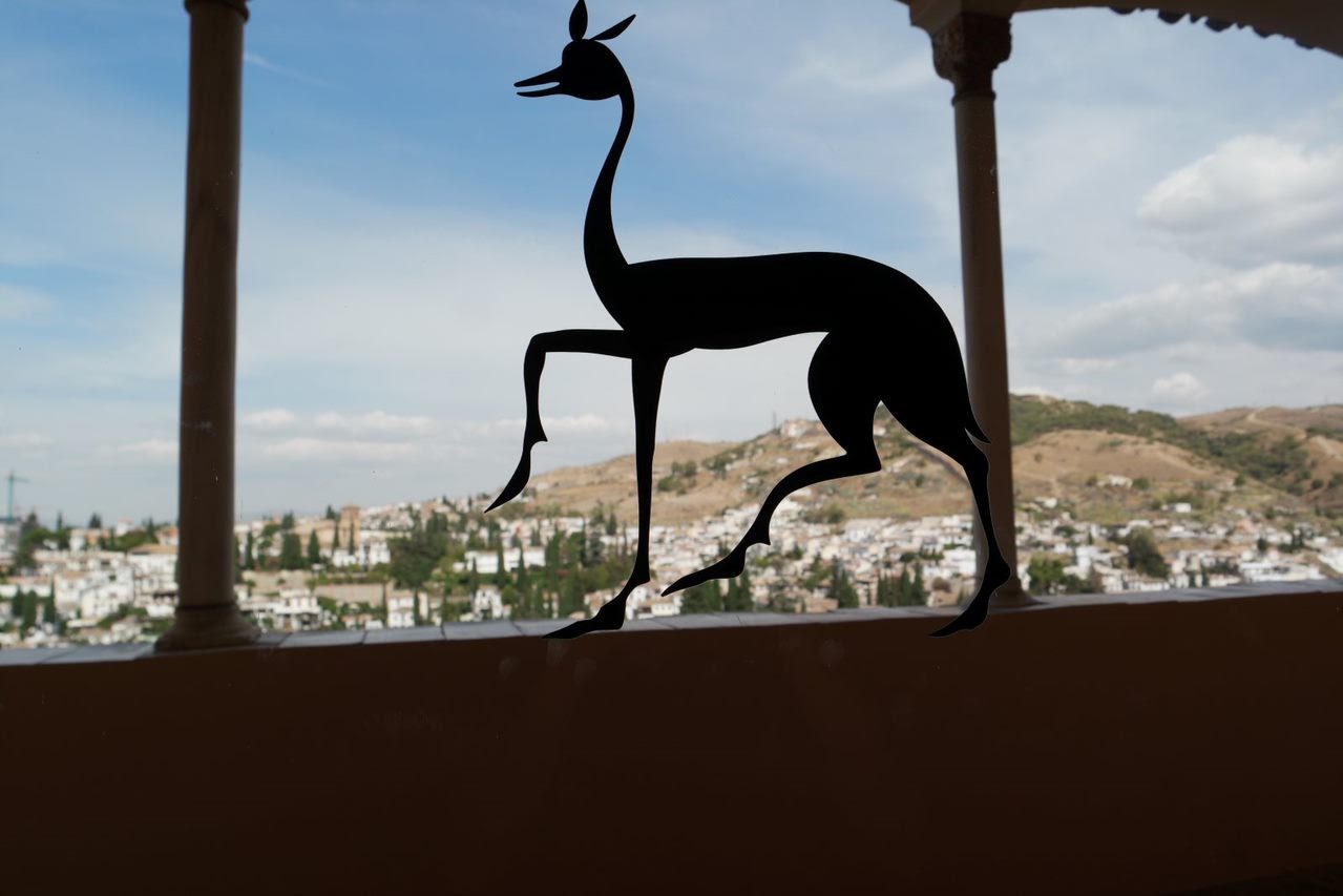 Deer-shaped silhouette between stone columns overlooking a hillside
