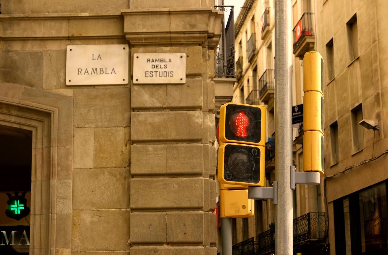 Pedestrian signal beside a narrow street and stone buildings