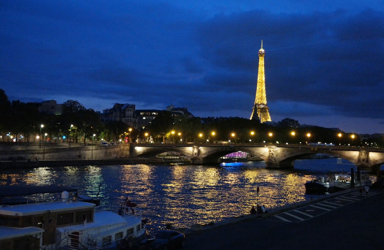 Illuminated tower and bridge reflected in a river at dusk